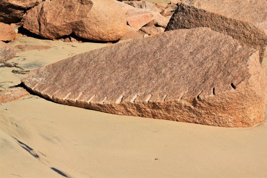 A pink granite block showing drill holes is left lying on the beach at Cape Woolamai granite quarry, Phillip Island.