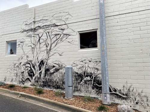 Mural of trees and grasses on brick wall.